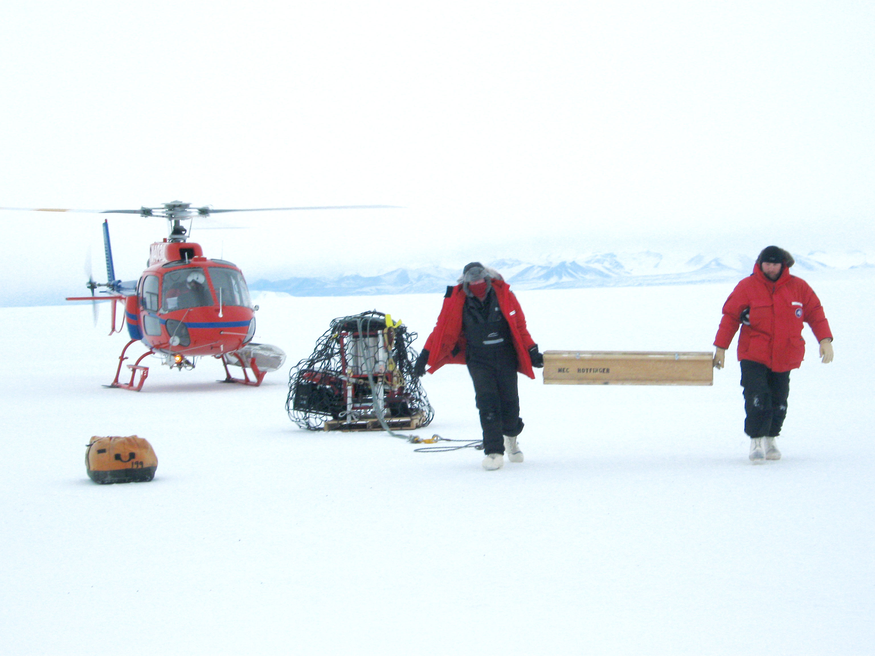 Two researchers just got out an helicopter landed on ice of Antarctica