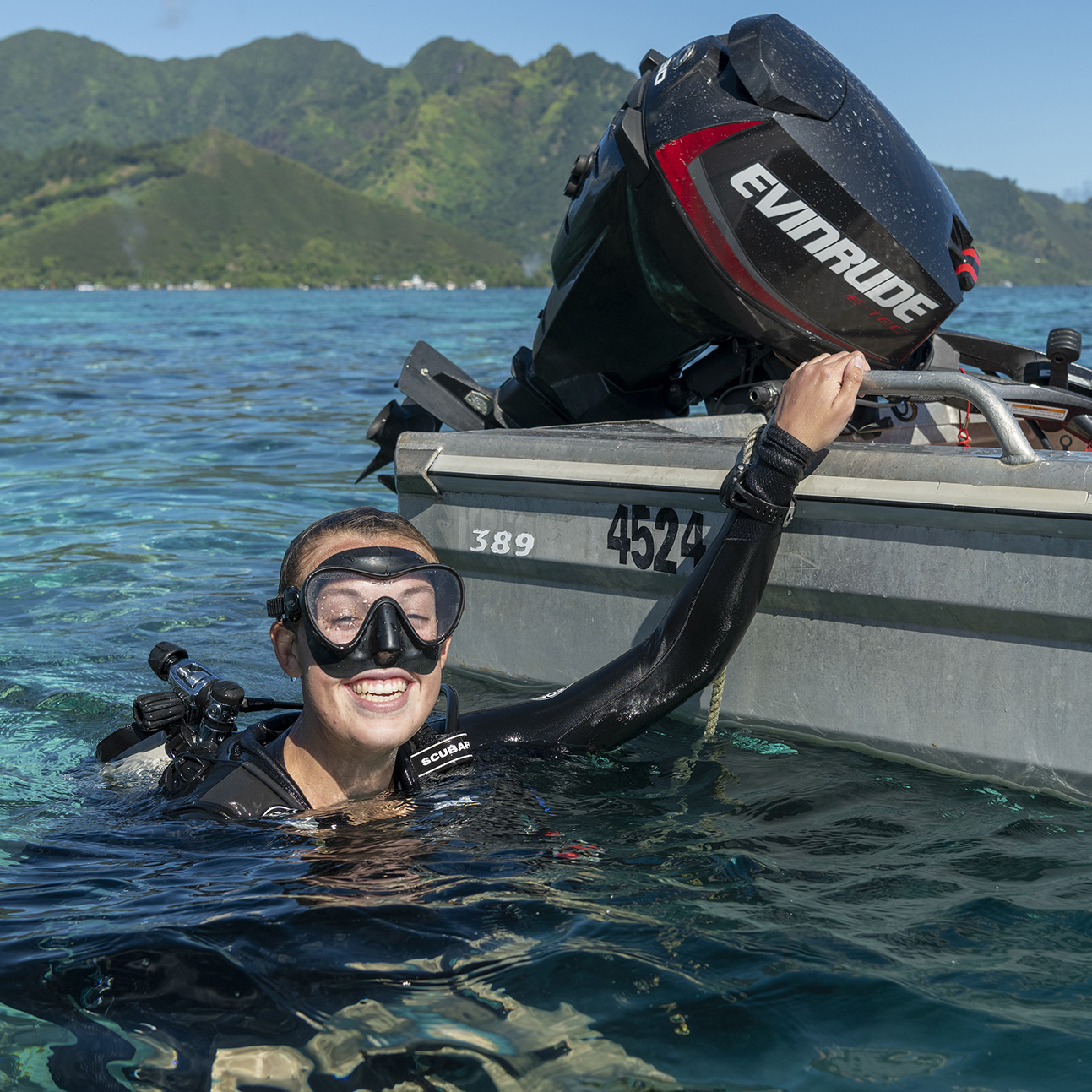 Smiling female diver surfacing by her boat