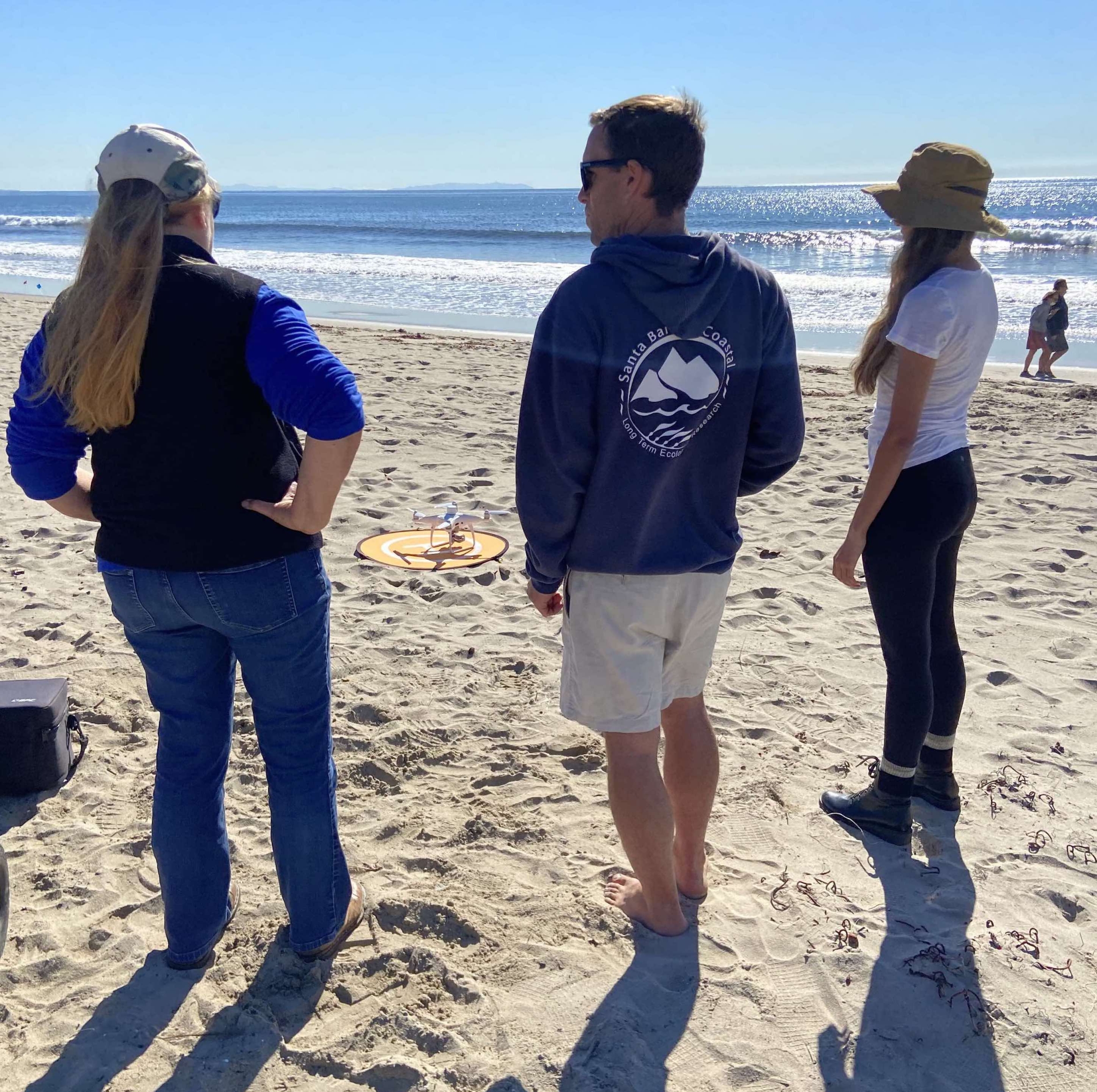 three people standing on sand