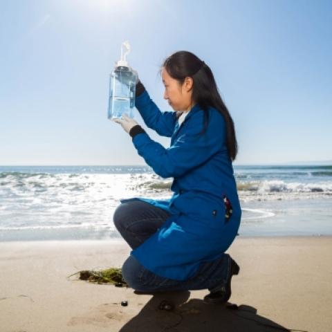 woman holds up a sample of seawater