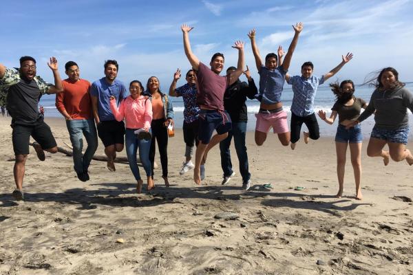 Students jumping together on the beach