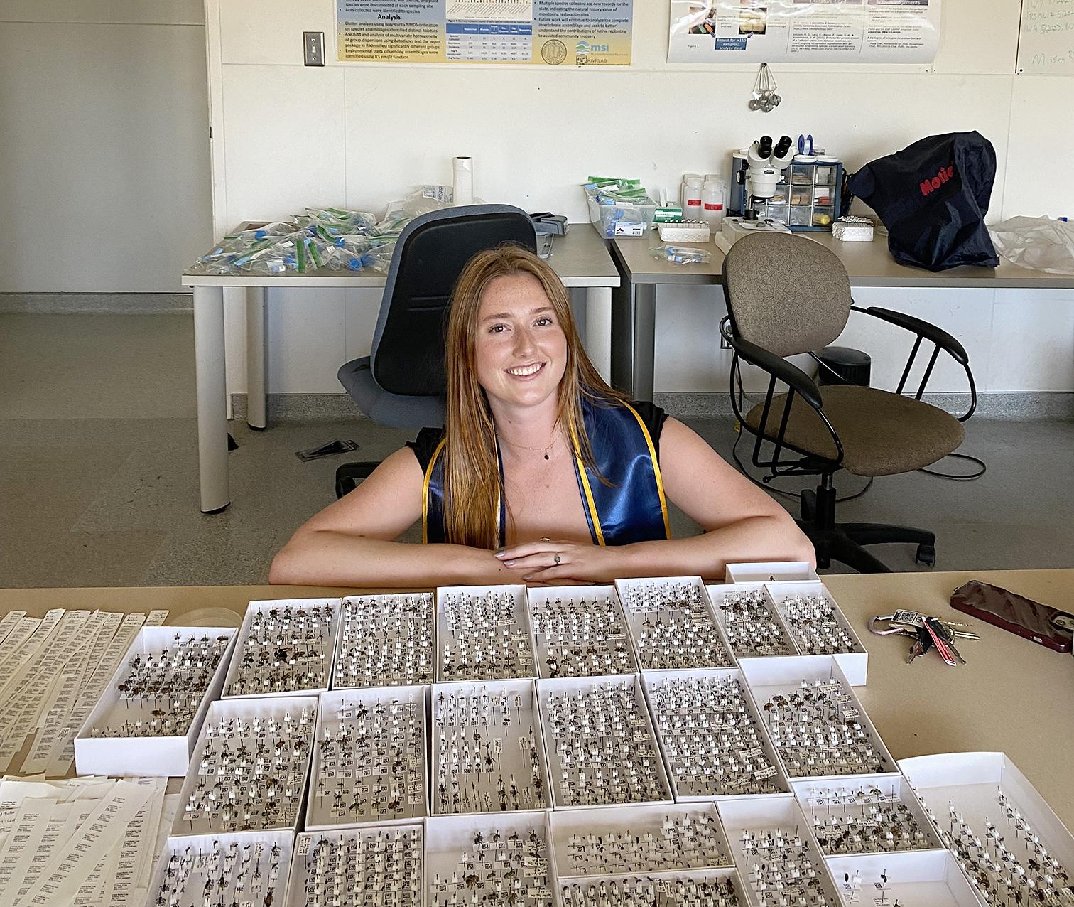 Jessie sitting behind a desk full of specimens