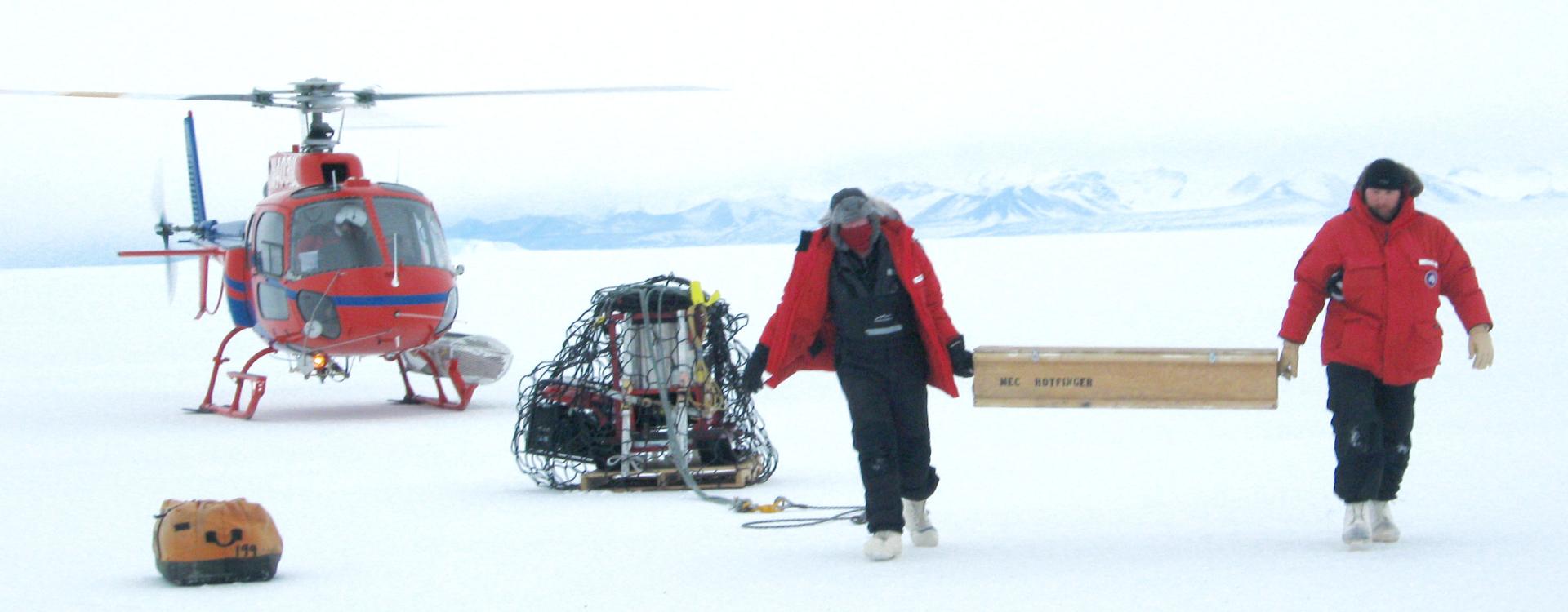 Two researchers just got out an helicopter landed on ice of Antarctica