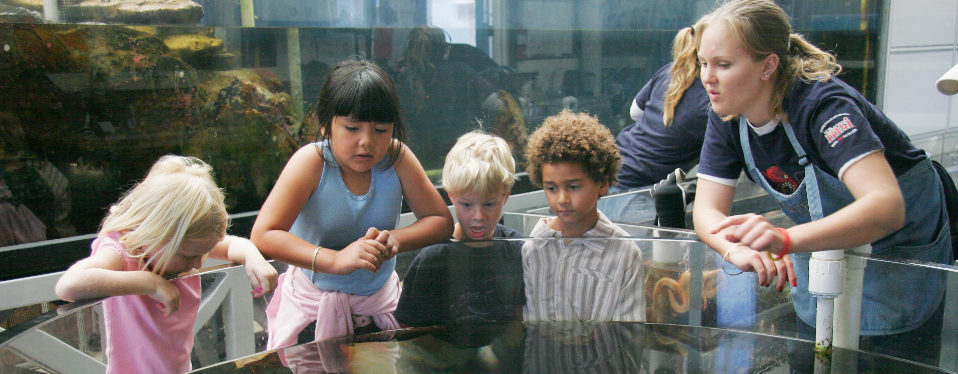 Kindergarten kids around aquarium listen to UCSB undergraduate student