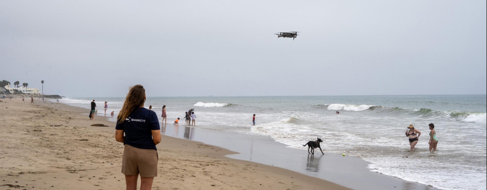 Researcher on the beach driving a drone in the sky