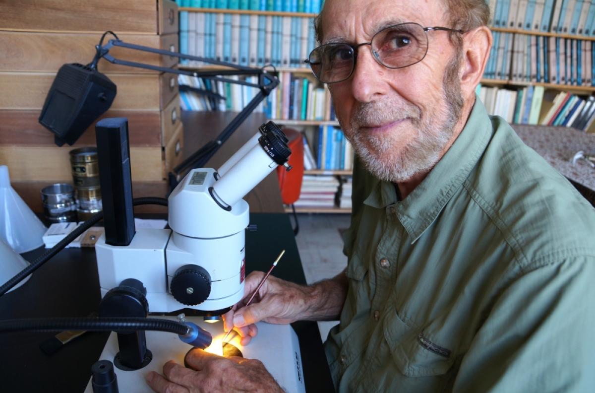 Professor emeritus James P. Kennett looking up from his microscope