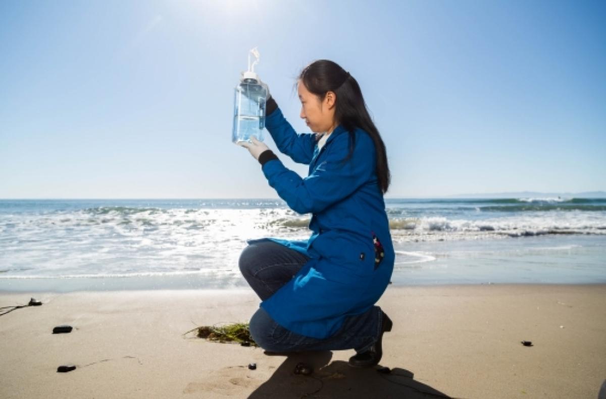 woman holds up a sample of seawater