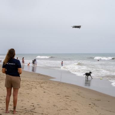 Researcher on the beach driving a drone in the sky