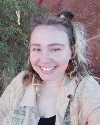 Siena smiling in front of red rocks and mesquite tree