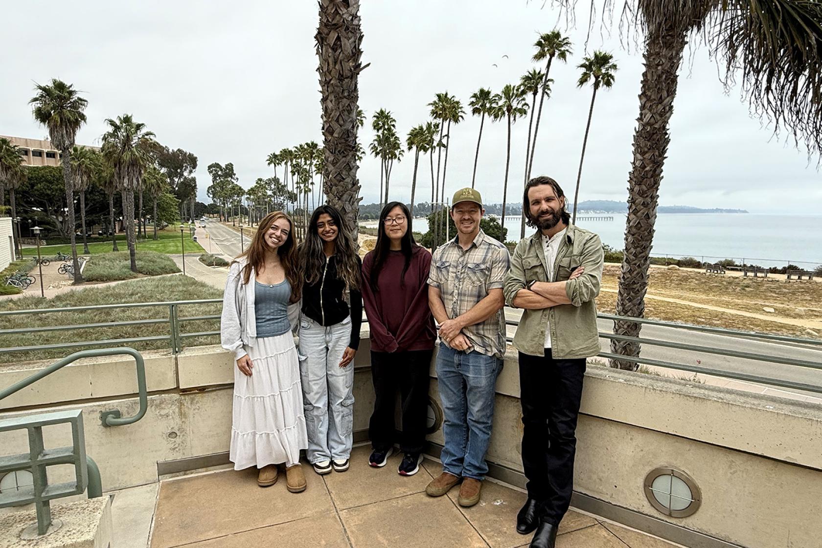 Analab crew posing for photo on the MSI balcony with view of palms and ocean in background