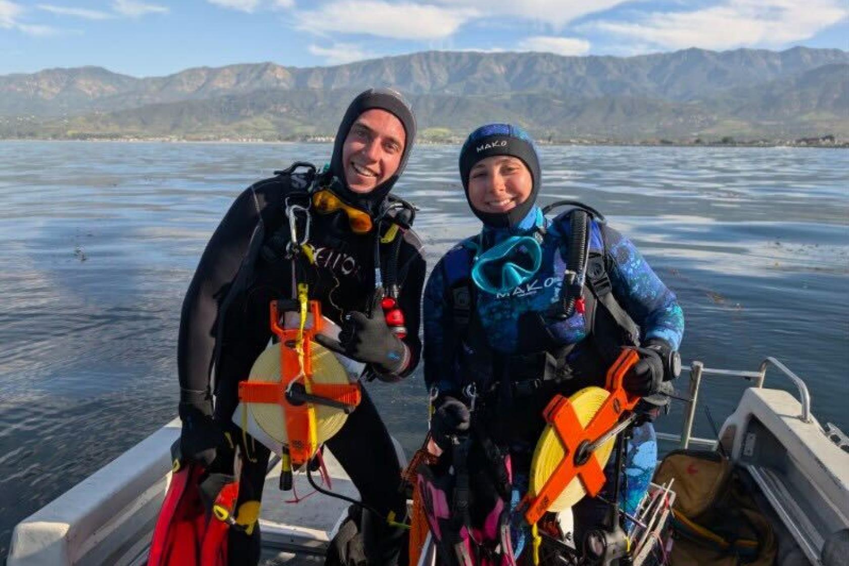 Avery (left) with diving buddy sitting on edge pf small boat ready to dive