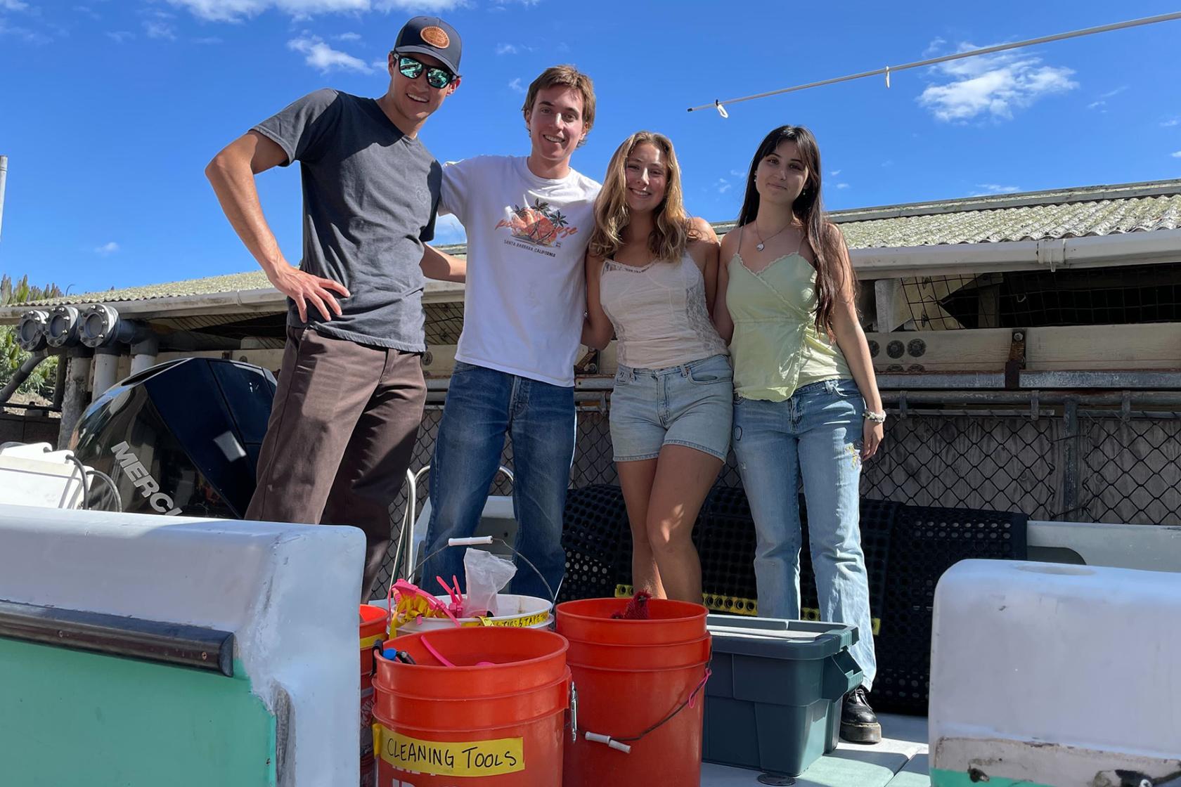 Group of four, Avery is third from left, posing in normal clothes in front of tools