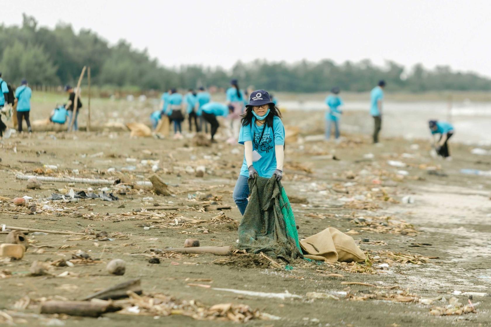 Volunteer pulling some trash laying on sand